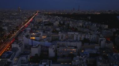Geceleri şehir merkezindeki binaların üzerinden ileriye doğru uçuyor. Charles de Gaulle Bulvarı ve Eyfel Kulesi çok yönlü. Paris, Fransa.