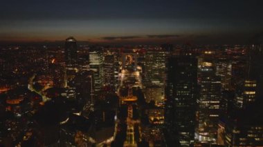 Geceleri Metropolis 'in havadan panoramik görüntüsü. Geriye doğru, La Defense bölgesindeki modern yüksek katlı ofis kuleleri boyunca uçar. Paris, Fransa.