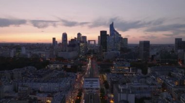 Günbatımında şehrin üzerinde ilerliyorlar. Günbatımı gökyüzüne karşı La Defans 'ta modern yüksek binalarla gökyüzü. Paris, Fransa.