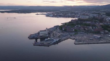 Liman terminali ve tarihi Akershus kalesinin havadan panoramik görüntüsü. Alacakaranlıkta sahilde bir şehir. Oslo, Norveç.