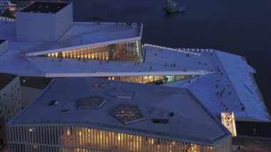 Günbatımında modern fütüristik tasarım Opera Binası 'nda gezinti ve gözcülük platformunda yürüyen yayalar. Oslo, Norveç.
