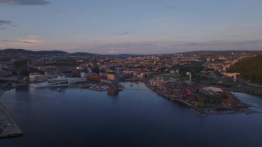 Şehrin son güneş ışınlarıyla aydınlatılan panoramik görüntüsü. Eski rıhtımlardaki modern şehir ilçeleri. Oslo, Norveç.