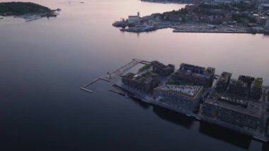 Gezinti güvertesi ve deniz suyu havuzuyla yeni şehir merkezinin yüksek açılı manzarası. Eğim, alacakaranlık rengi yansıtan su yüzeyini ortaya çıkarır. Oslo, Norveç.