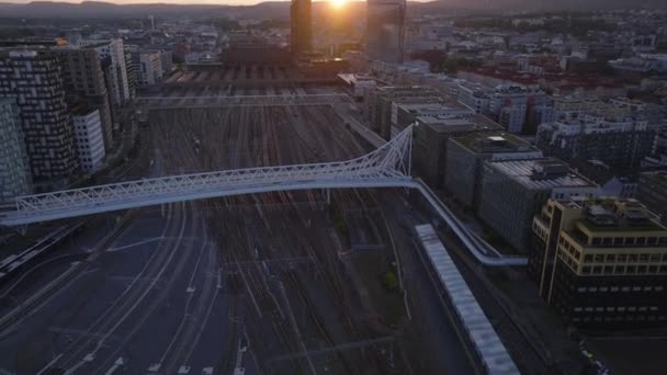 中央駅の鉄道線上に架かる未来的なデザインのノルデンガ橋の空中観察 太陽を沈めることに対する街並みを明らかにする オスロ ノルウェー — ストック動画
