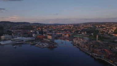 İleriye doğru altın saatte suyun üzerinde uçar. Şehirdeki binaların havadan görüntüsü. Opera Oslo 'nun modern fütürist binası. Oslo, Norveç.