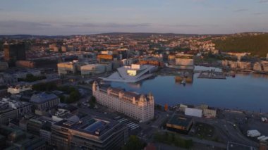 Şehir merkezindeki hava kaydırak ve pan görüntüleri güneş batarken aydınlatılıyor. Rıhtımdaki Opera Oslo 'nun modern tasarım binası. Oslo, Norveç.