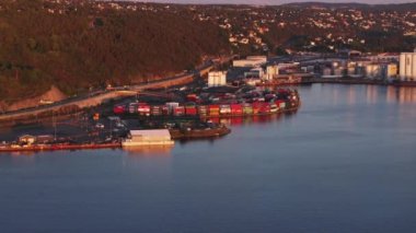 Limandaki lojistik terminalin havadan görüntüsü. Rıhtımdaki renkli konteynırlar batan güneşle aydınlatılıyor. Oslo, Norveç.