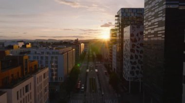 Modern yerleşim yerlerinde sokağın üzerinden geriye doğru uçun. Renkli günbatımına karşı görüş. Oslo, Norveç.