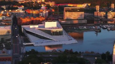Opera Oslo 'nun fütüristik tasarım binasının havadan slayt ve pan görüntüleri. İnsanlar rıhtımda altın saatin tadını çıkarıyorlar. Oslo, Norveç.