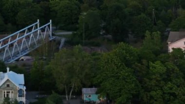 Banliyöden geçen banliyö treninin yan takibi. Ağaçlar ve mülklerle çevrili demiryolu hattı. Helsinki, Finlandiya.