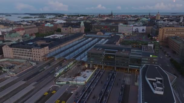 在中央火车站上空飞行 站在月台上的火车黄昏时的城市景观 运输和物流概念 芬兰赫尔辛基 — 图库视频影像