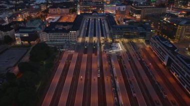 Akşamları Central tren istasyonundaki tren ve platformların yüksek açılı görüntüsü. Yukarıya doğru eğildiğinde deniz uzaklığı ile birlikte şehir manzarası ortaya çıkar. Helsinki, Finlandiya.