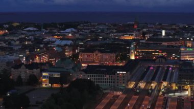 Akşam şehrinin hava görüntüleri. Şehir merkezinin yakınındaki tren istasyonunda çeşitli binalar. Arka planda deniz var. Helsinki, Finlandiya.