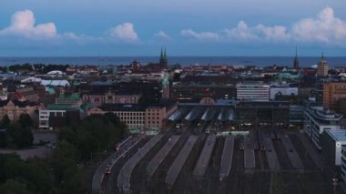 Tren istasyonunun havadan görüntüsü, binalar ve arka planda deniz ve şehir manzarası. Metropolis alacakaranlıkta. Helsinki, Finlandiya.