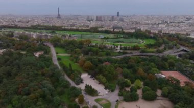 Şehirdeki parktaki yeşilliğin hava görüntüleri. Şehir gelişimi ve turistik manzaralı şehir manzarası. Eyfel Kulesi ve Otomatik Hipodrom. Paris, Fransa.