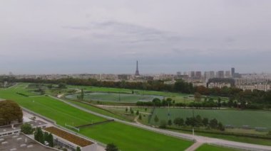 Arazili ve hipodromlu büyük spor alanlarının hava panoramik görüntüleri. Apartman binaları ve arka planda uzun Eyfel kulesi. Metropolis 'te bulutlu bir gün. Paris, Fransa.