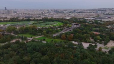 Ağaçlı ve spor salonlu büyük parkın hava kaydırak ve pan görüntüleri. Metropolis 'e giden çok şeritli bir yol var. Paris, Fransa.