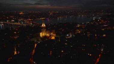 Seyahat merkezindeki popüler turist manzarası etrafında geriye doğru uçmak. Aydınlatılmış Galata Kulesi ve akşam manzarası. İstanbul, Türkiye.