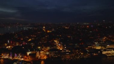 Aydınlatılmış sokaklar ve binalarla gece manzarasının yükselen görüntüsü. Rıhtım ve popüler tarihi Galata Kulesi. İstanbul, Türkiye.