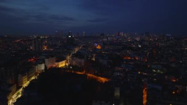 Aydınlatılmış cadde ve şehir merkezindeki binalar. Arka planda modern yüksek katlı ofis binaları olan metropolün hava akşam manzarası. İstanbul, Türkiye.