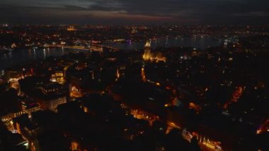 Akşam metropolünün hava panoramik görüntüsü. Aydınlatılmış sokaklar ve büyük şehirlerdeki binalar. Tepedeki tarihi Galata Kulesi. İstanbul, Türkiye.