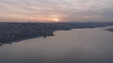 Metropolis 'in alacakaranlıktaki hava panoramik görüntüleri. Geniş nehir kıyısında büyük bir şehir. Güneş bulutların ardında batıyor. İstanbul, Türkiye.