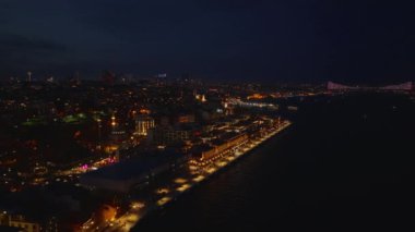 Galataport kompleksindeki aydınlatılmış rıhtımın etrafında uç. Akşam metropolünün hava panoramik görüntüsü. Uzakta Boğaz Köprüsü var. İstanbul, Türkiye.