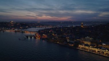 Akşam metropolünün hava ve pan görüntüleri. Şehir ilçelerini birbirine bağlayan geniş nehir üzerinde aydınlatılmış köprüler. İstanbul, Türkiye.
