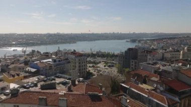 Şehir merkezindeki binaların üstünde ilerliyorlar. Nehir ya da körfez boyunca şehirde trafik var. İstanbul, Türkiye.