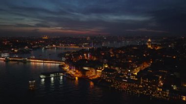 Akşam şehrinin inanılmaz sinematik görüntüleri. Rıhtım ve köprü üzerindeki su yayan binalar. İstanbul, Türkiye.