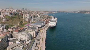 Rıhtımdaki ve büyük yolcu gemisindeki kentsel binalar. Boğaz sularının havadan görünüşü. İstanbul, Türkiye.