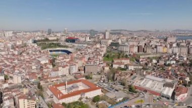 Güneşli bir günde büyük şehrin üzerinde uç. Şehir merkezindeki yoğun şehir gelişimi. Çok katlı evler ve spor stadyumu. İstanbul, Türkiye.