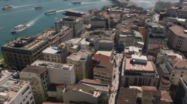 Şehir merkezindeki çok katlı binaların yüksek açılı manzarası. Yukarı doğru eğildiğinde şehirdeki su üzerindeki tekne trafiği, camiler ve diğer kıyılardaki diğer görüntüler ortaya çıkıyor. İstanbul, Türkiye.