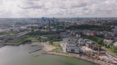 Metropolis 'in kayma ve yan görüntüsü. Deniz kıyısındaki konutlar, tarihi şehir merkezinde turistik yerler ve arka planda ofis kuleleri. Tallinn, Estonya.