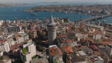 Tarihi Galata Kulesi 'nin ve eski kasabadaki binaların havadan görünüşü. Arka planda suda yüzen tekneler. İstanbul, Türkiye.