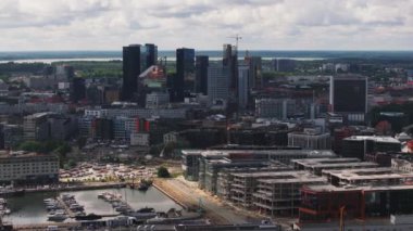Şehir marinasındaki modern şehir gelişiminin hava görüntüleri. İskeleye demirlemiş yatlar ve yelkenliler. Yüksek katlı ofis binaları olan modern kentsel bir mahalle. Tallinn, Estonya.