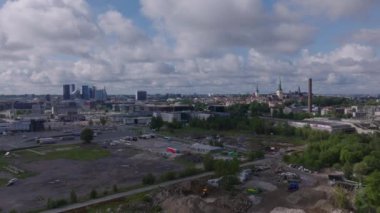 Depolanmış malzeme yığınlarıyla kumsal manzarası. Modern yüksek binaları ve arka planda tarihi turistik manzaraları olan bir şehir. Tallinn, Estonya.