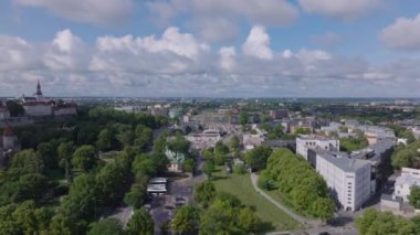 Forvetler parktaki ağaçların üzerinden ve nakliye terminali olan tren istasyonundan uçar. Şehrin havadan görünüşü. Tallinn, Estonya.