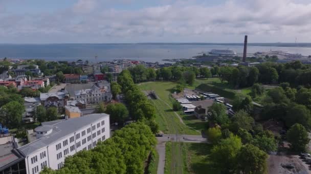 トラム停留所で停車する路面電車の空中視界 植生の緑地に囲まれたトラック 海岸沿いの住宅都市部の住宅 タリン エストニア — ストック動画