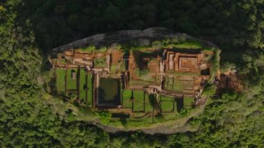 Ormanlık arazinin üstündeki yüksek kayalıkların tepesindeki terasların ve antik sarayın kalıntılarının en tepedeki görüntüsü. Popüler turist manzarası. Sigirya, Sri Lanka.