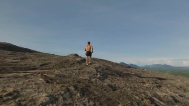 Kayalık yüzeyde koşan üstsüz sporcuyu takip ediyoruz. Nefes kesici panoramik manzara görüntüsü. Sigirya, Sri Lanka.