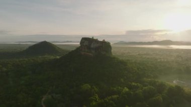 Sigirya Kayası ve çevresindeki ağaçlar güneşin doğuşuyla aydınlandı. Sabah manzarasının nefes kesici panoramik manzarası. Sigirya, Sri Lanka.