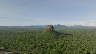 Güneşli bir günde ağaçlık arazinin havadan panoramik görüntüsü. Ormanın üzerinde yükselen kayalık çıkıntıları ortaya çıkarıyor. Sigirya, Sri Lanka.