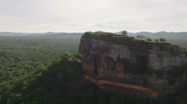 Uçsuz bucaksız ormanlarla çevrili yüksek kayalıklardaki tarihi kalenin hava görüntüleri. Antik sarayın kalıntılarını gözler önüne seriyor. Sigirya, Sri Lanka.