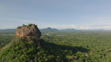 Sigirya Kayası 'nın etrafında ileri doğru uçun. Üzerinde antik sarayın kalıntıları olan popüler bir turist manzarası. Havadan panoramik manzara görüntüleri. Sigirya, Sri Lanka.