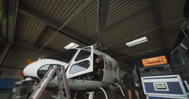 ハンガーでヘリコプターで作業する技術者の低角度ビュー 追加の機器のメンテナンスと設置 空港と航空コンセプト ベルリン ドイツ 2019 — ストック動画