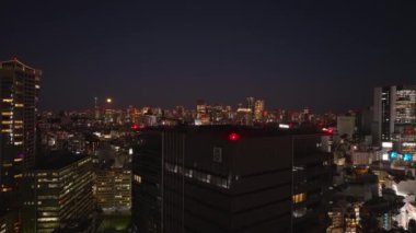 Şehirdeki çok katlı binanın havadan yükselen görüntüleri. Metropolis 'in gece manzarası ortaya çıkıyor. Tokyo, Japonya.