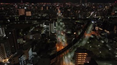 Metropolis 'te geceleri şehir merkezindeki cadde ve apartman manzaralı evler. Arabalar akşam şehrinden geçiyor. Osaka, Japonya.
