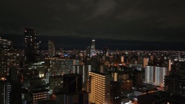 İleri uçaklar gece Metropolis 'teki konutların üzerinde uçuyor. Çok katlı apartmanların akşam görüntüsü. Osaka, Japonya.