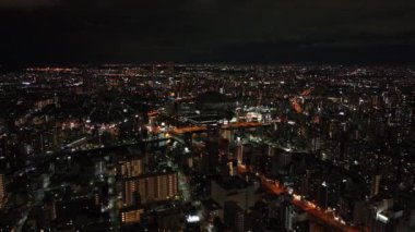 İleri, Gece Şehri 'nin üzerinde uçar. Modern yüksek binaları olan büyük bir şehrin panoramik görüntüsü. Osaka, Japonya.